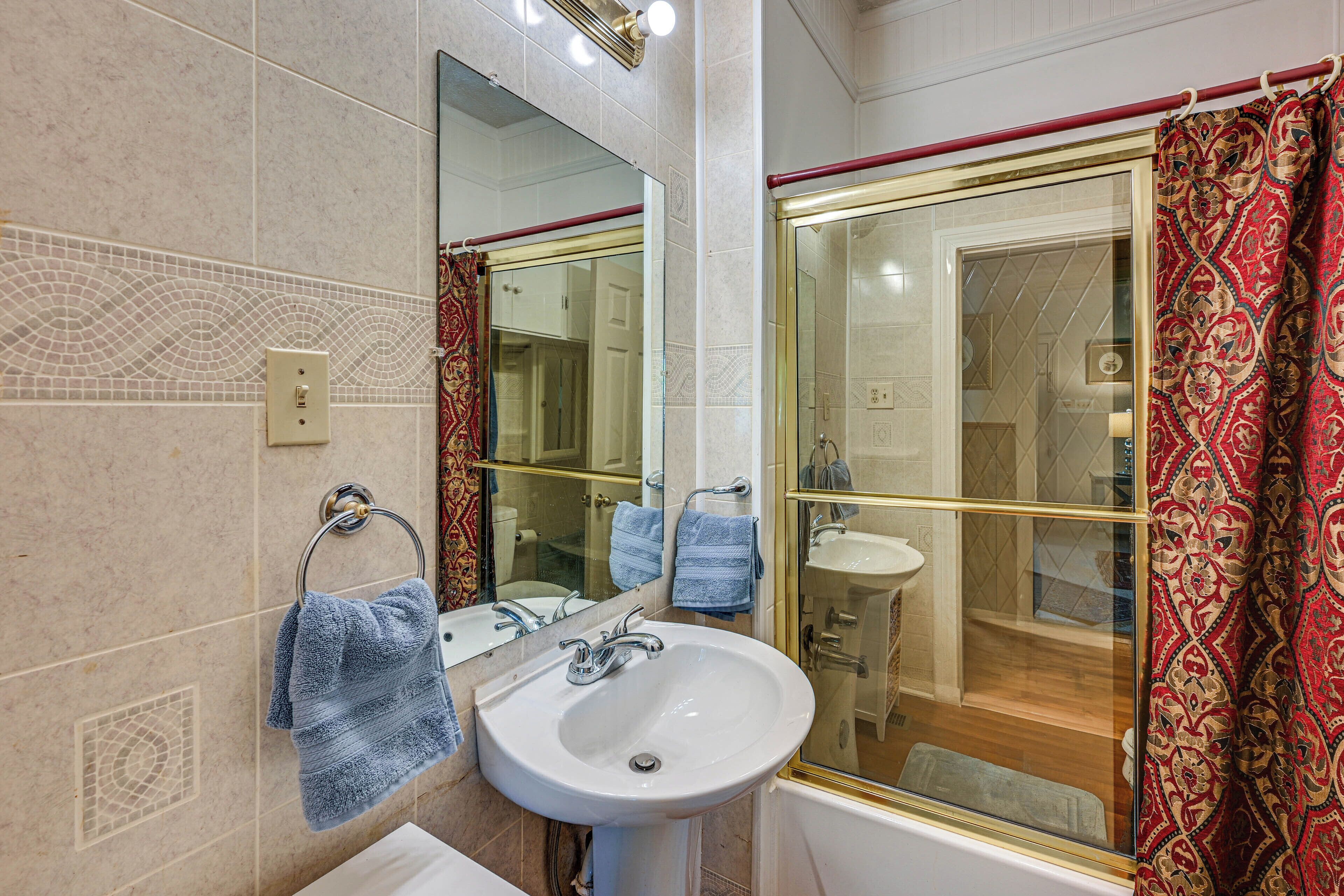 A bathroom with a sink, mirror, and shower area.