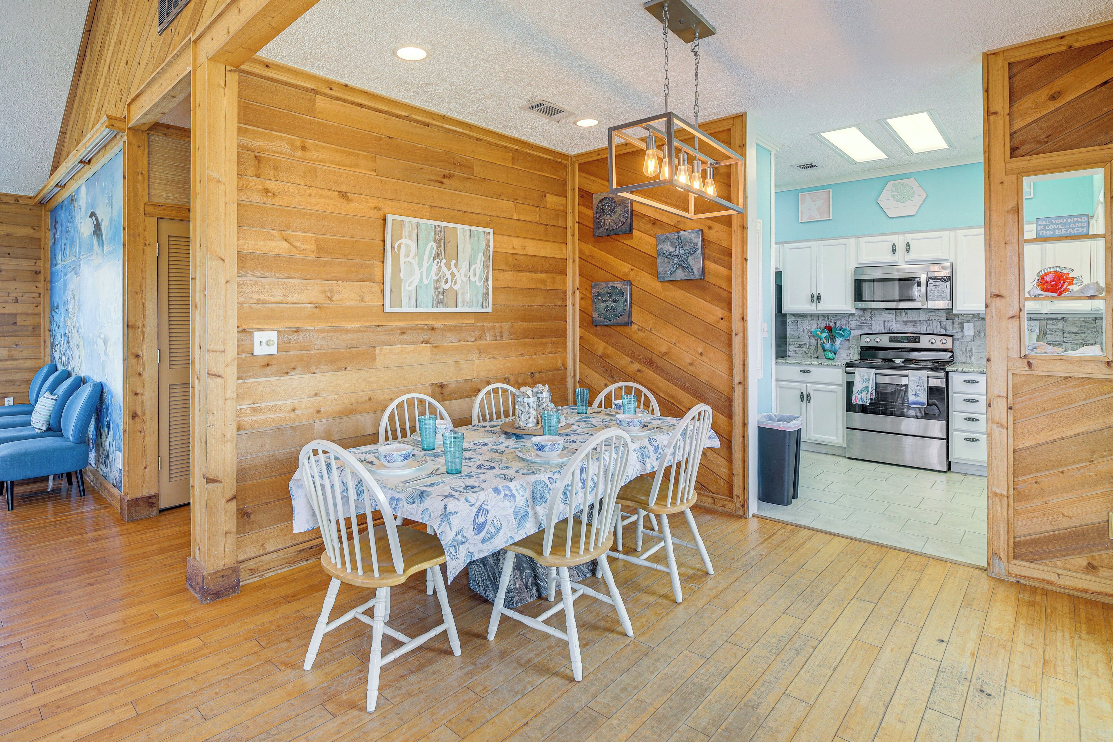 A wooden interior with a dining area, kitchen, and a blue wall with a 'Blessed' sign.