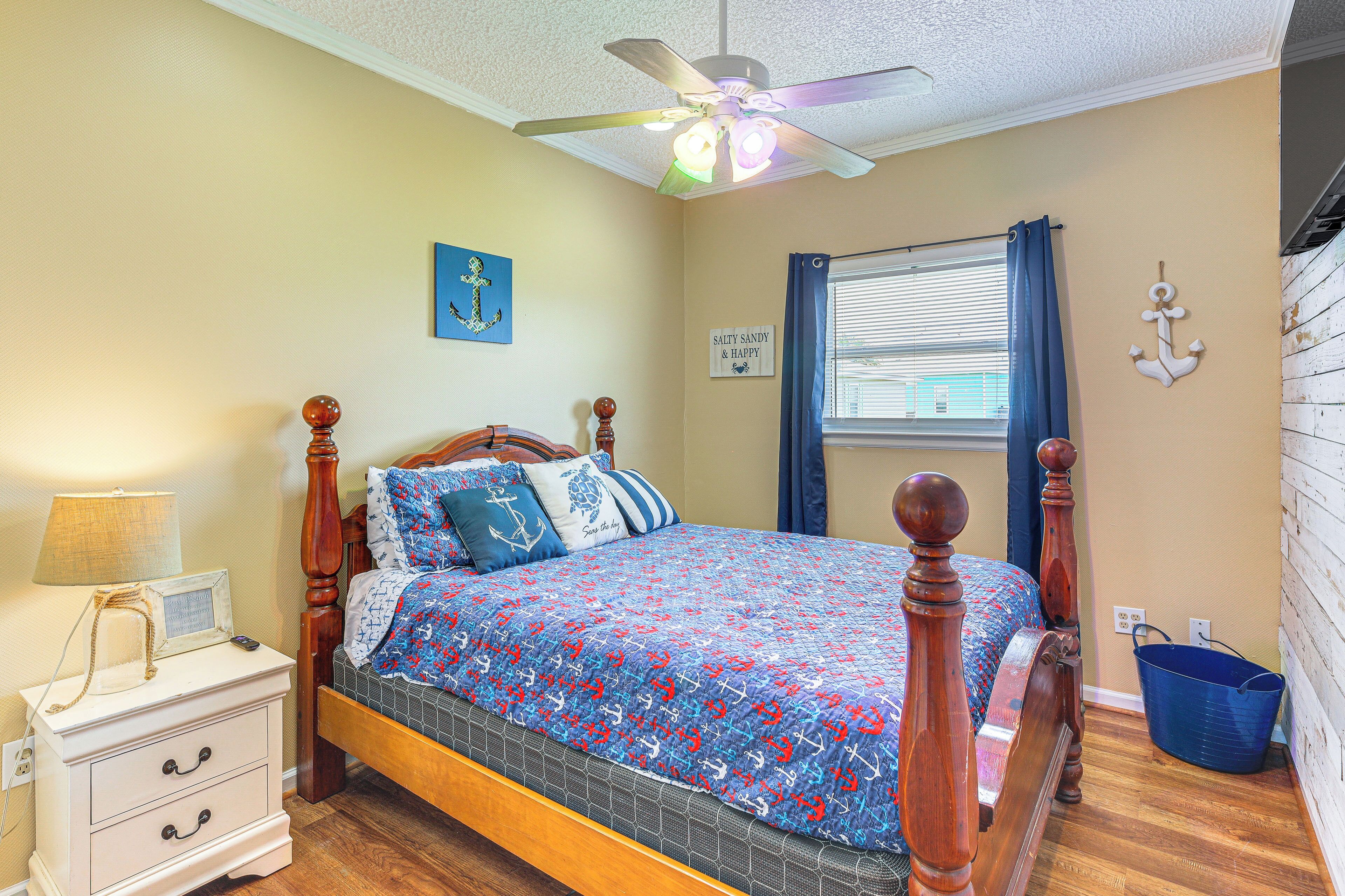 A bedroom with a wooden bed, a nightstand, a ceiling fan, and a window with curtains.