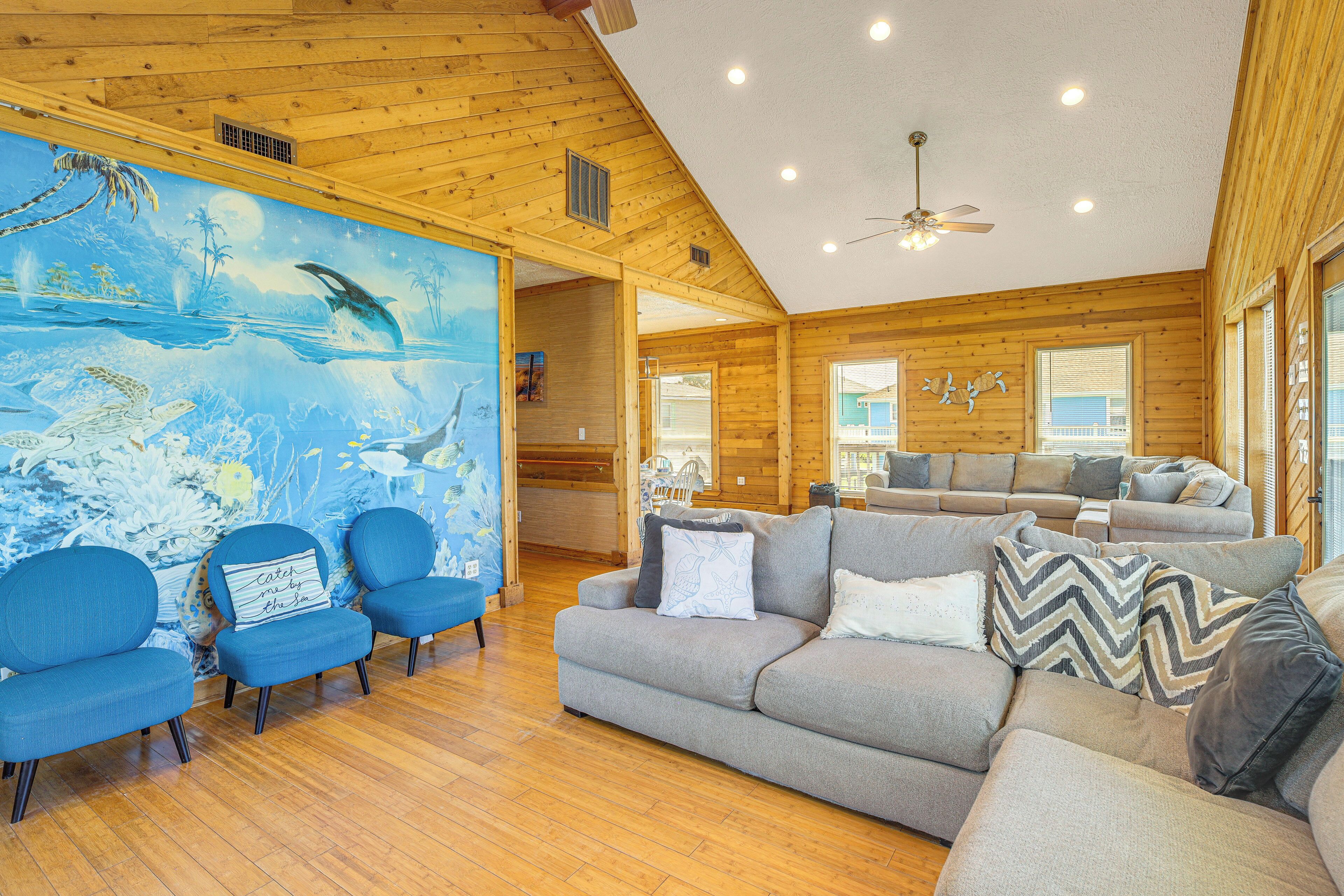 A spacious living room with a wooden ceiling, a large mural, and a modern sofa set.