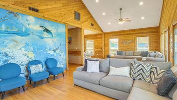 A spacious living room with a wooden ceiling, a large mural, and a modern sofa set.