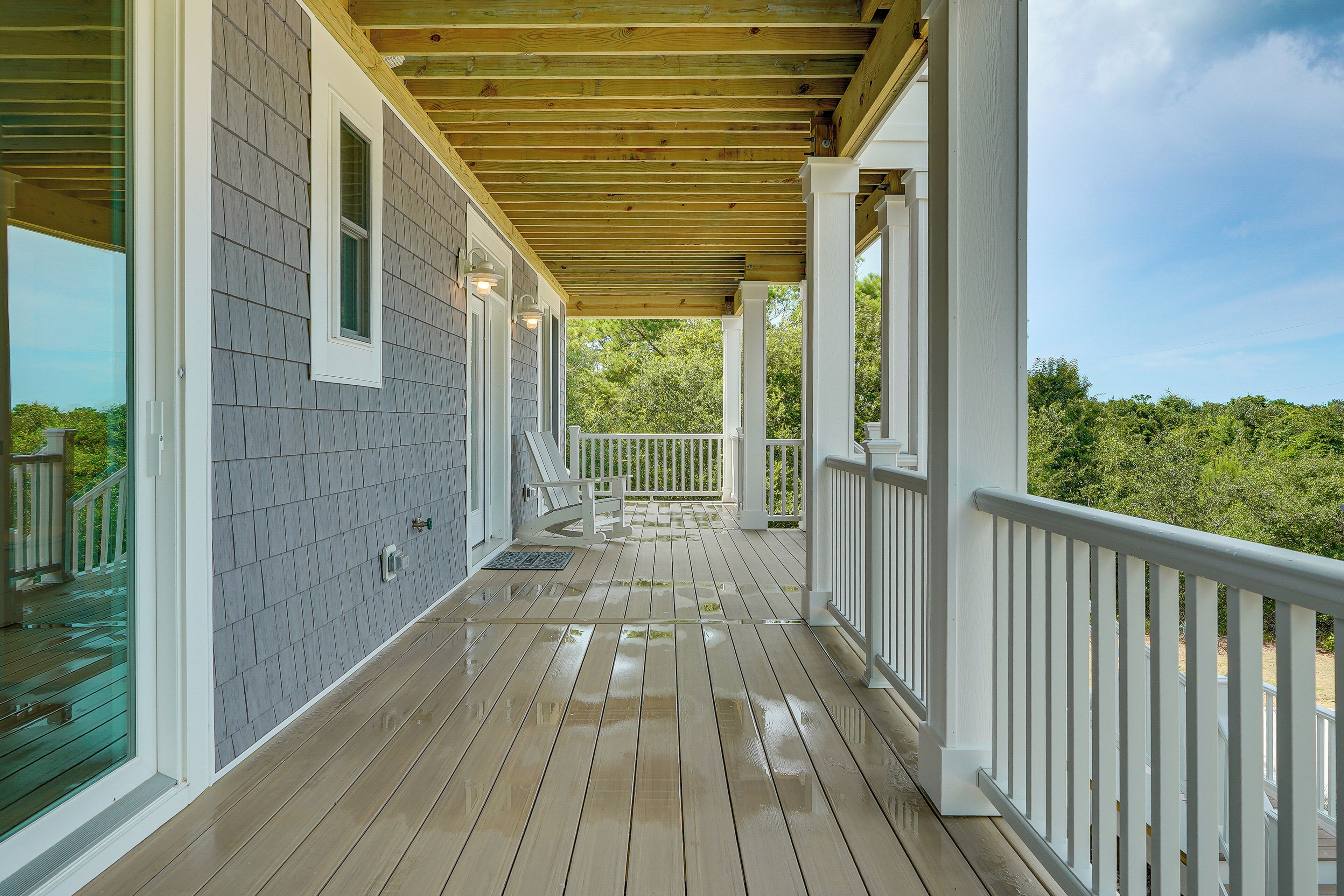 A covered porch with a wooden floor and white railings.