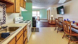 A kitchen with wooden cabinets, a white stove, and a dining area with a wooden table and chairs.