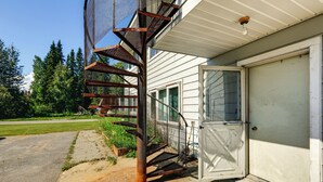 A metal spiral staircase leading to a garage door, surrounded by a concrete driveway and a grassy area.