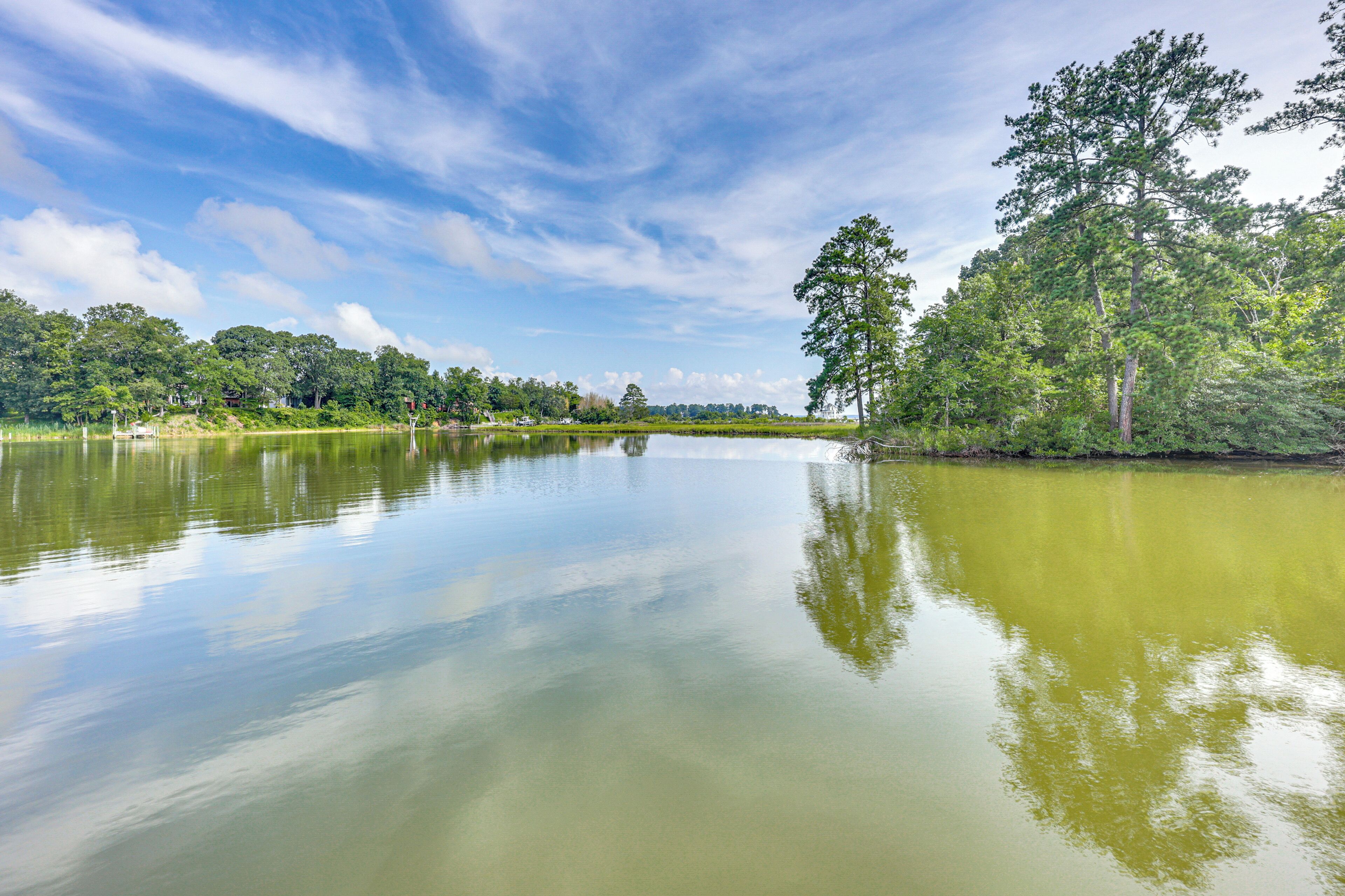 Un lac paisible dont les eaux reflètent clairement le ciel et les arbres environnants.