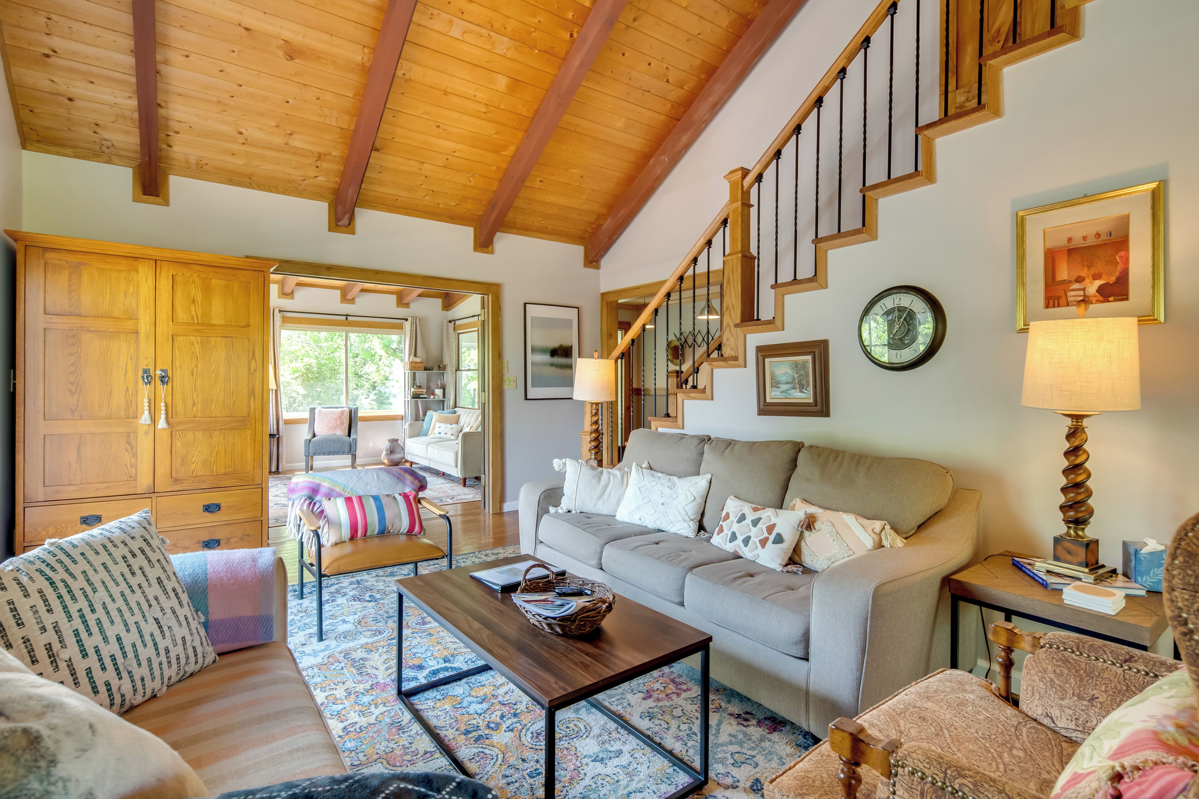 Un salón acogedor con techo de madera, un sofá, una mesa de centro y una escalera.