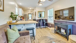 A modern kitchen with a central island, bar stools, and a dining area with a table and chairs.
