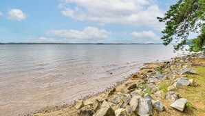 A rocky shoreline with clear water and distant land.