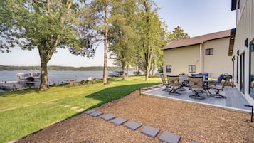 A lakeside property with a deck, outdoor seating, and a view of the water.
