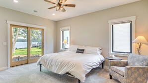 A bedroom with a bed, a chair, a lamp, and a view of a lake through a sliding door. - Lake Wapogasset Home w/ Dock: 7 Mi to Amery (Amery)