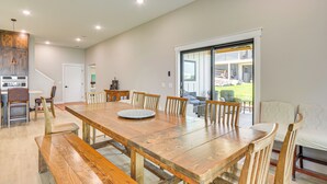 A spacious dining area with a large wooden table and benches, a kitchen area with a built-in oven, and a sliding glass door leading to a patio. - Lake Wapogasset Home w/ Dock: 7 Mi to Amery (Amery)