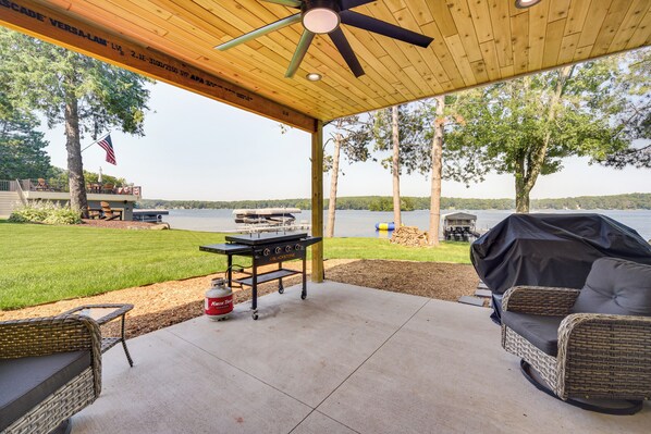 Un patio exterior con una parrilla, asientos y vistas al lago.