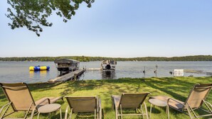 A lakeside view with a dock, lounge chairs, and a floating platform. - Lake Wapogasset Home w/ Dock: 7 Mi to Amery (Amery)