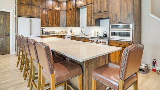 A kitchen with wooden cabinets, a central island with bar stools, stainless steel appliances, and pendant lighting. - Lake Wapogasset Home w/ Dock: 7 Mi to Amery (Amery)