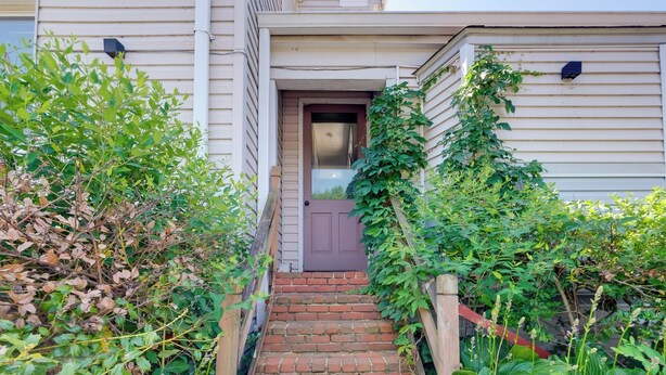 A set of brick stairs leading to a front door of a house with a wooden fence on one side and overgrown vegetation on the other. - Near Loudoun Wine Trail: Apt w/ Restaurant On-site (Hamilton)