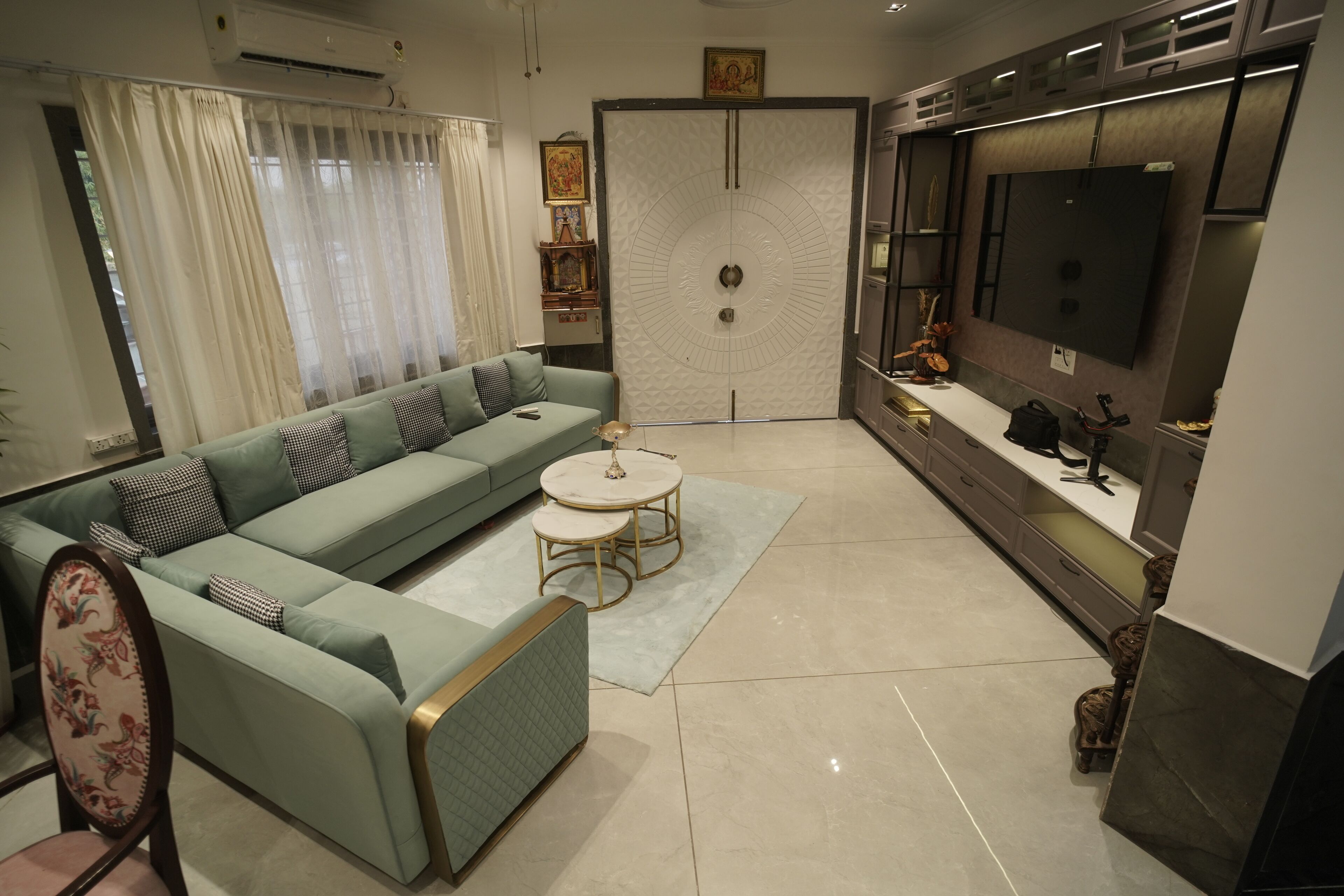 A modern living room with a sectional sofa, a round coffee table, and a flat-screen TV mounted on the wall.