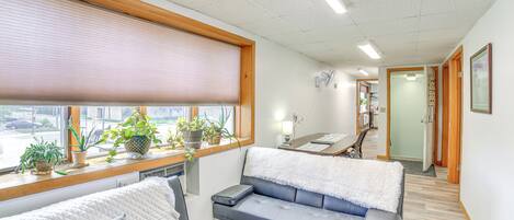 Et moderne hotelværelse med sofa, sengebord og et vindue med persienner.