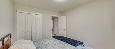 A bedroom with a bed, a wardrobe, and a door leading to another room.