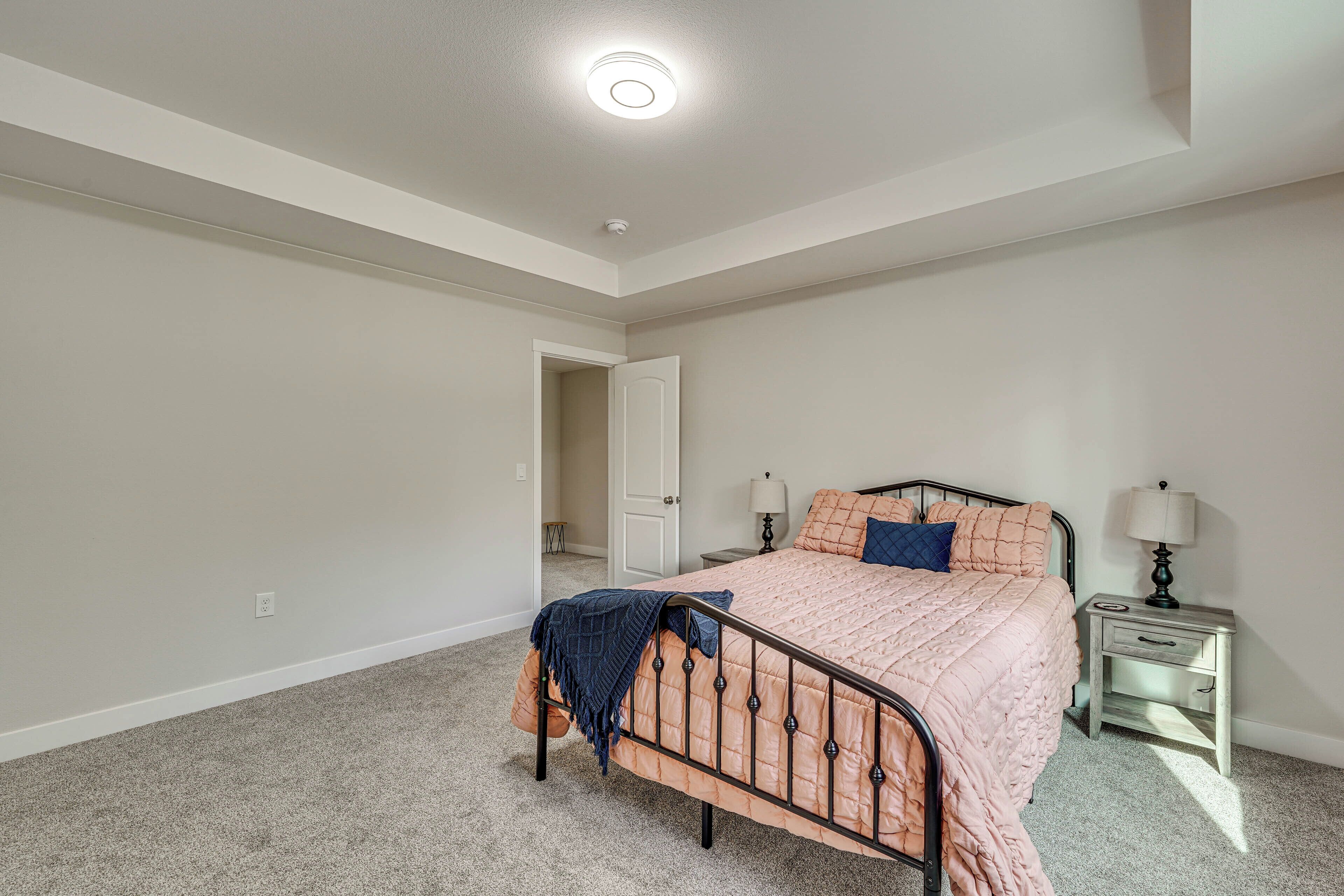 A bedroom with a bed, nightstands, and a door leading to another room.