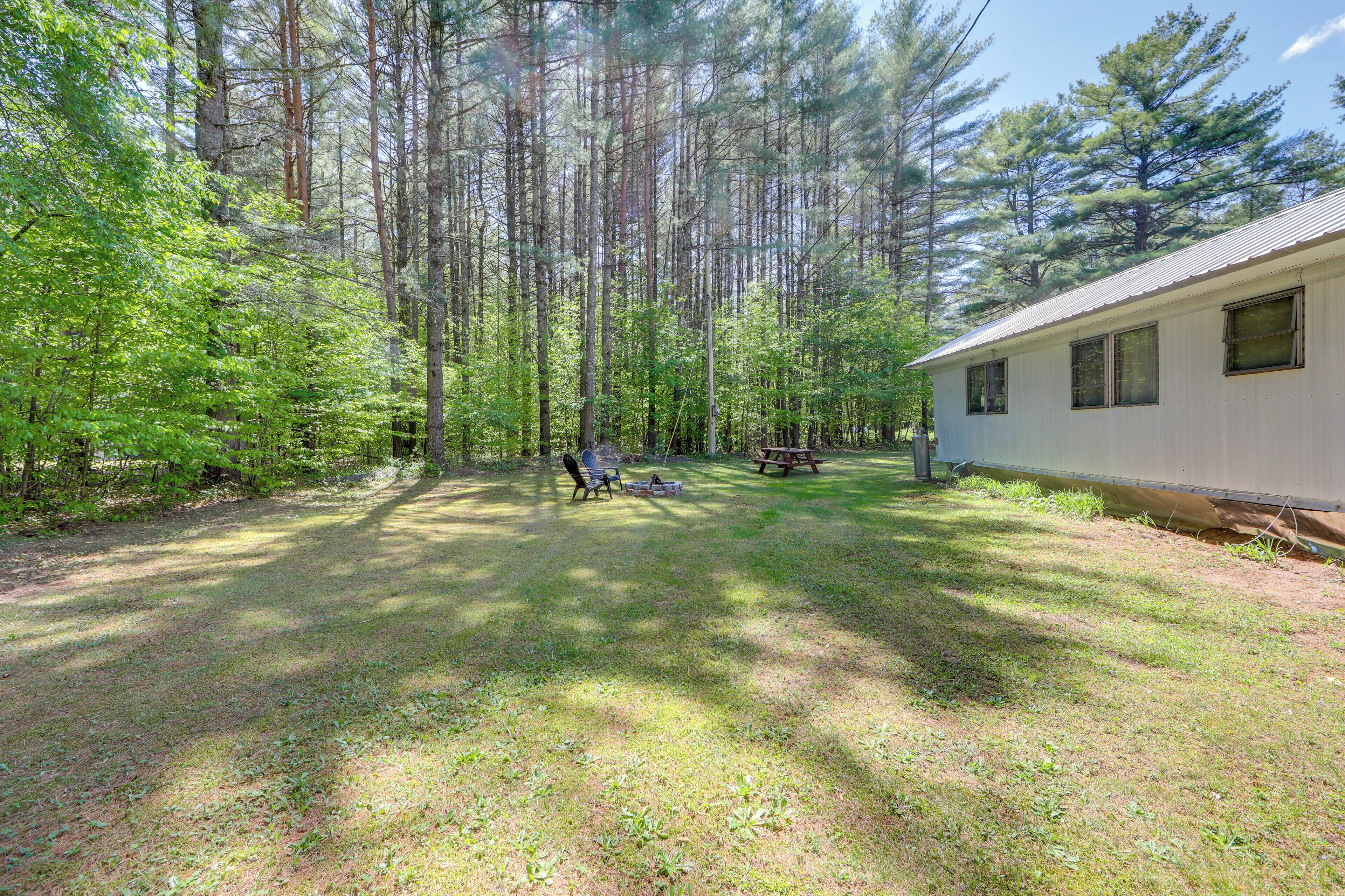 A cabin with a grassy yard, a picnic table, and a chair.