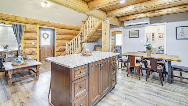 Interior rústico de una cabaña con una escalera de madera, una isla de cocina y un comedor.