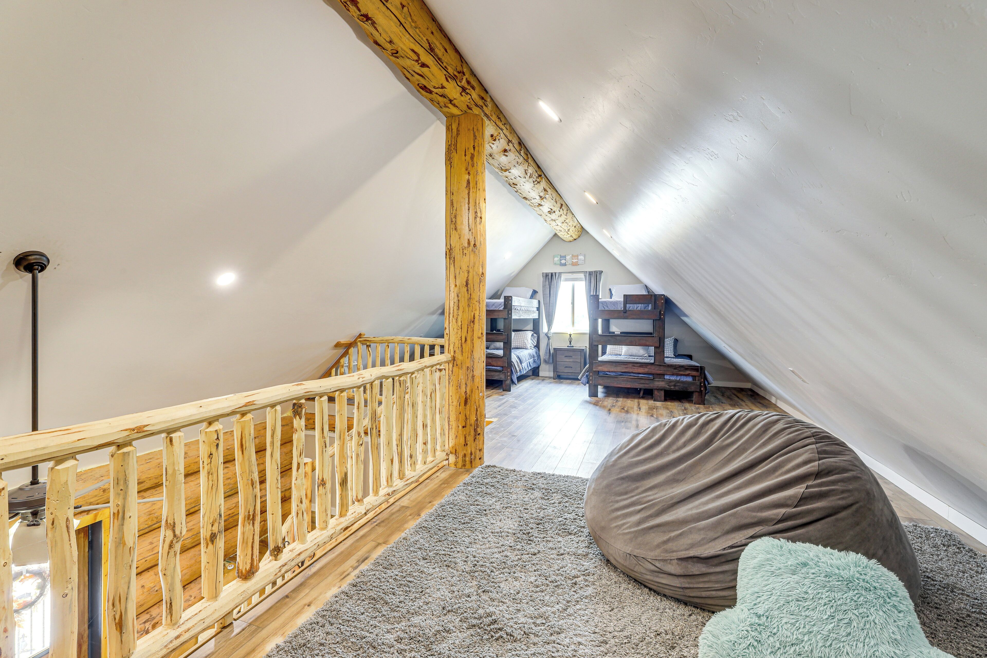 Une chambre en mezzanine avec un escalier en bois, un grand fauteuil poire et une vue sur la pièce adjacente.