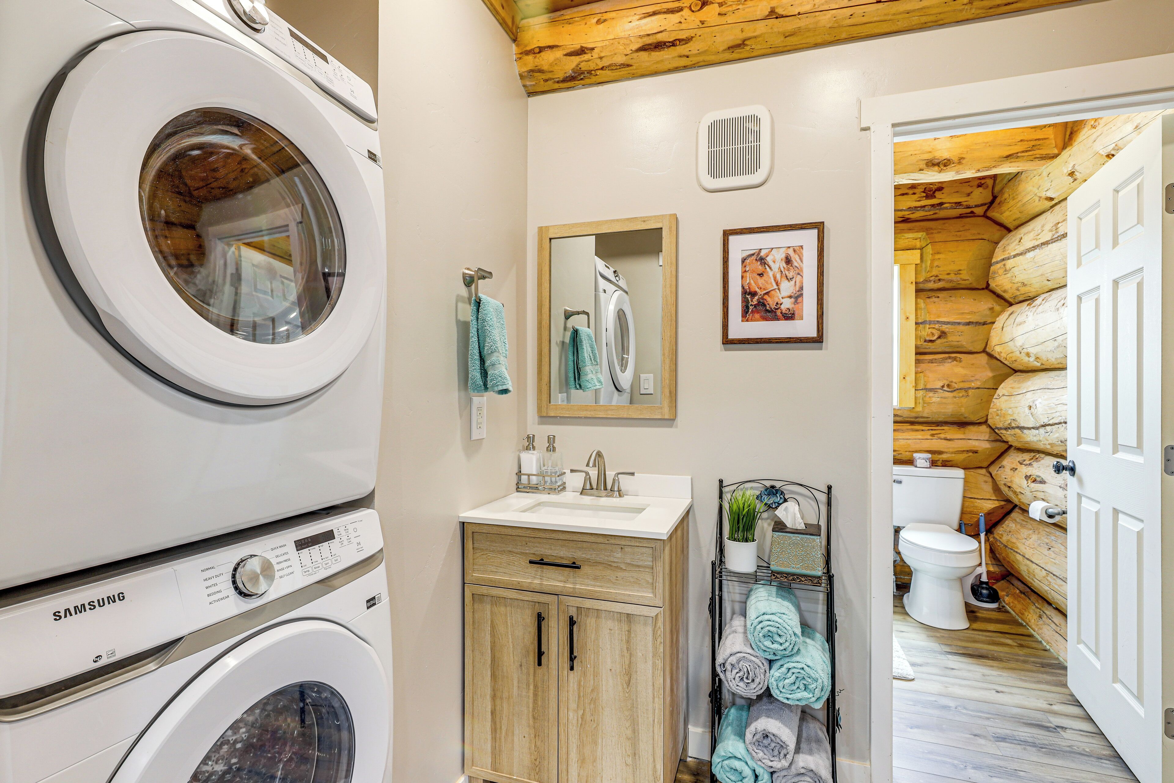 A laundry area with stacked washers and dryers, a sink, and a mirror.
