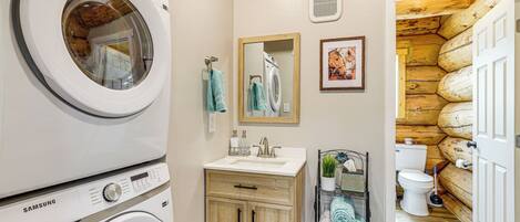 A laundry area with stacked washers and dryers, a sink, and a mirror.