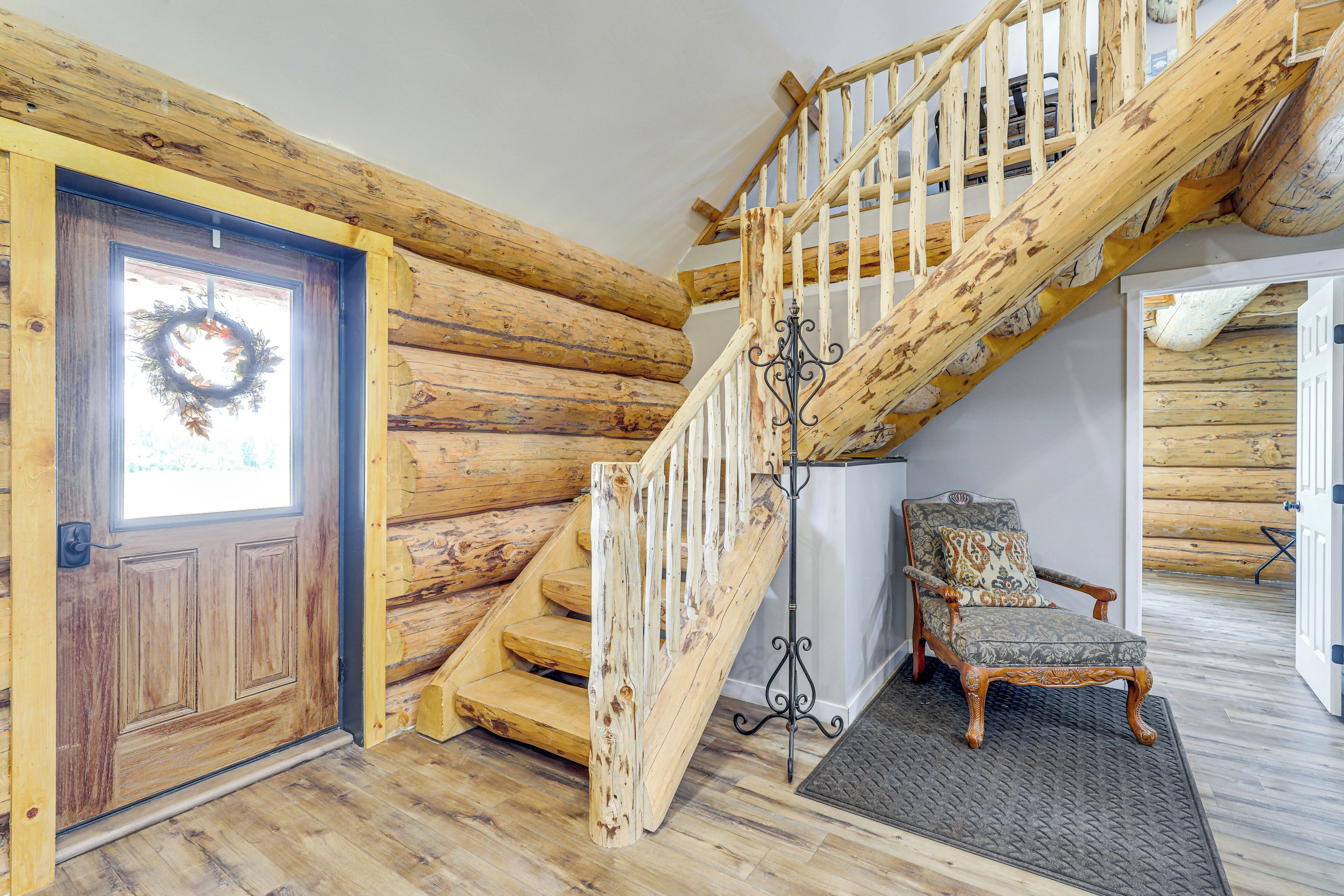 Una scala in legno con una porta di legno e una sedia in un interno di baita.