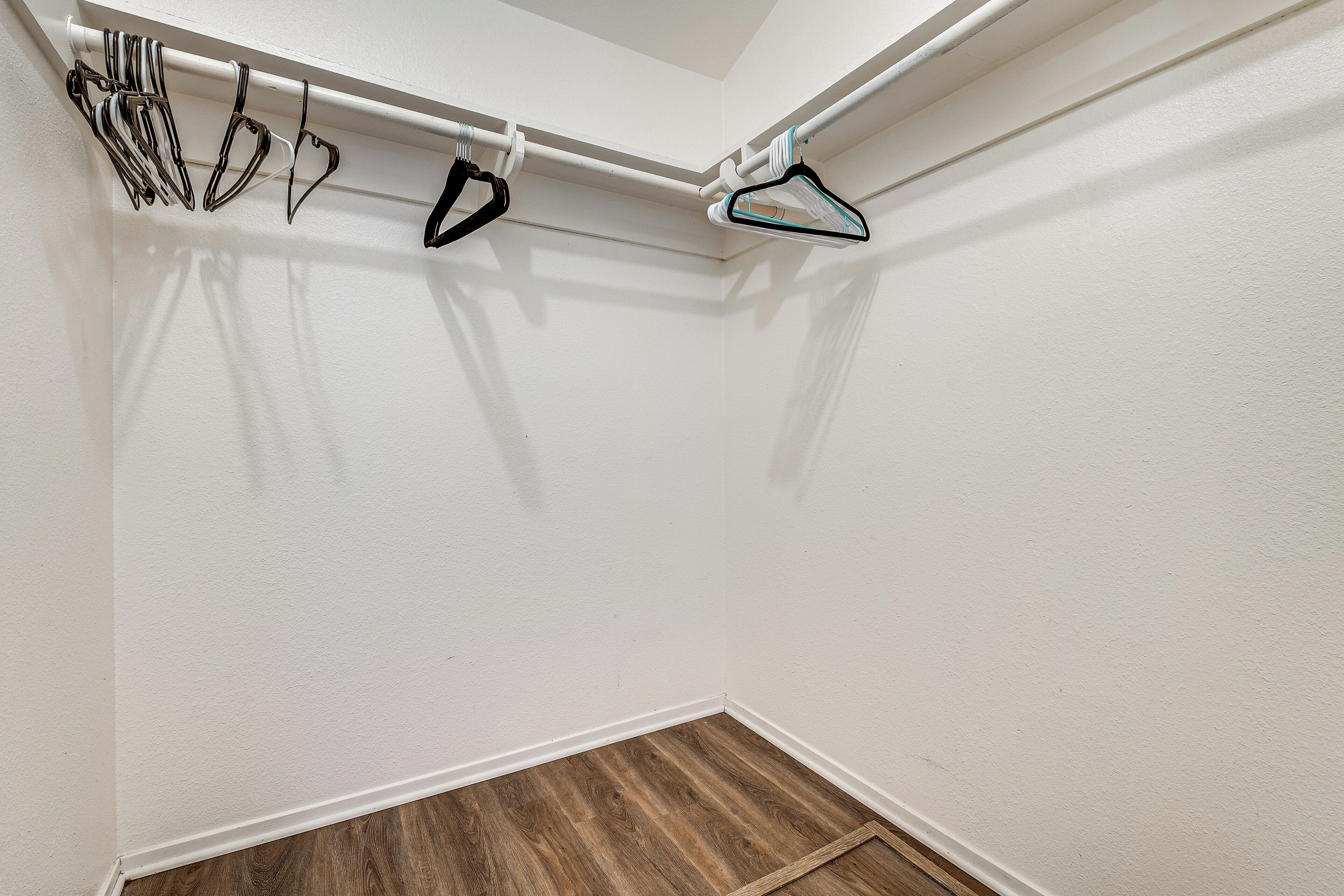 Esquina de una habitación con pared blanca, suelo de madera y techo blanco.