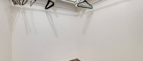 Esquina de una habitación con pared blanca, suelo de madera y techo blanco.