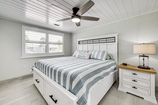 A bedroom with a bed, a nightstand, a ceiling fan, a window, and a lamp. - Steps to Englewood Beach: Home w/ Outdoor Oasis! (Englewood)