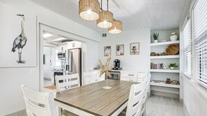 Una cocina moderna con armarios blancos, una mesa de comedor de madera y una lámpara colgante.