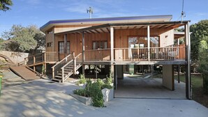 Ein zweigeschossiges Holzhaus mit Balkon, Treppe und überdachter Terrasse.