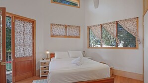 Ein Schlafzimmer mit einem hölzernen Bett, einem Nachttisch, einer Lampe und einem Fenster mit Vorhängen.