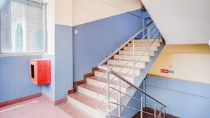 A staircase with metal railings, a red fire alarm box, and a blue wall. - Collection O Last Gate Formerly RR Hotels (Guwahati)