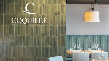 Ein Restaurantinneres mit einer grünen Wand aus Fliesen, einem Holztisch, der mit Gläsern und Besteck gedeckt ist, und einer blauen Polsterbank.