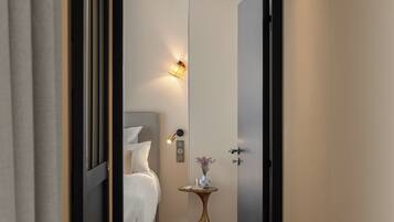 Un pasillo estrecho que conduce a un dormitorio con cama, mesita de noche e iluminación en la pared.