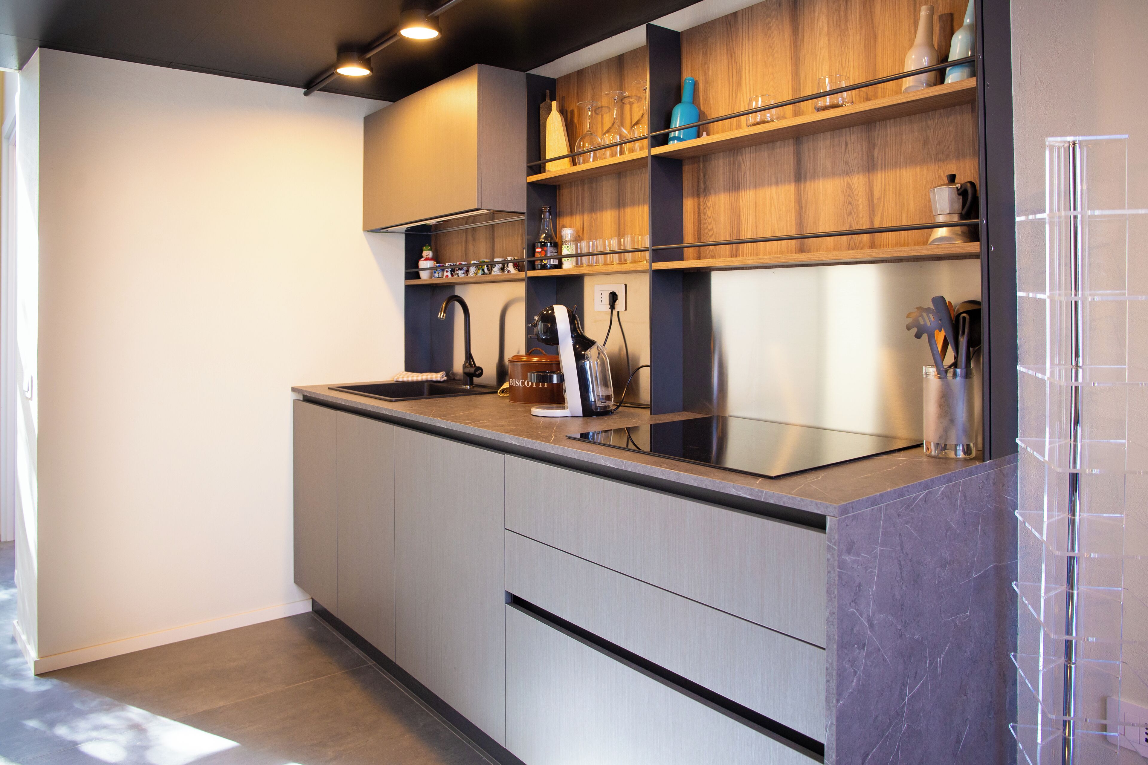 A modern kitchen with a built-in stove, a sink, and wooden shelves.