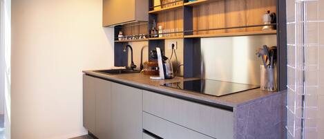 A modern kitchen with a built-in stove, a sink, and wooden shelves.