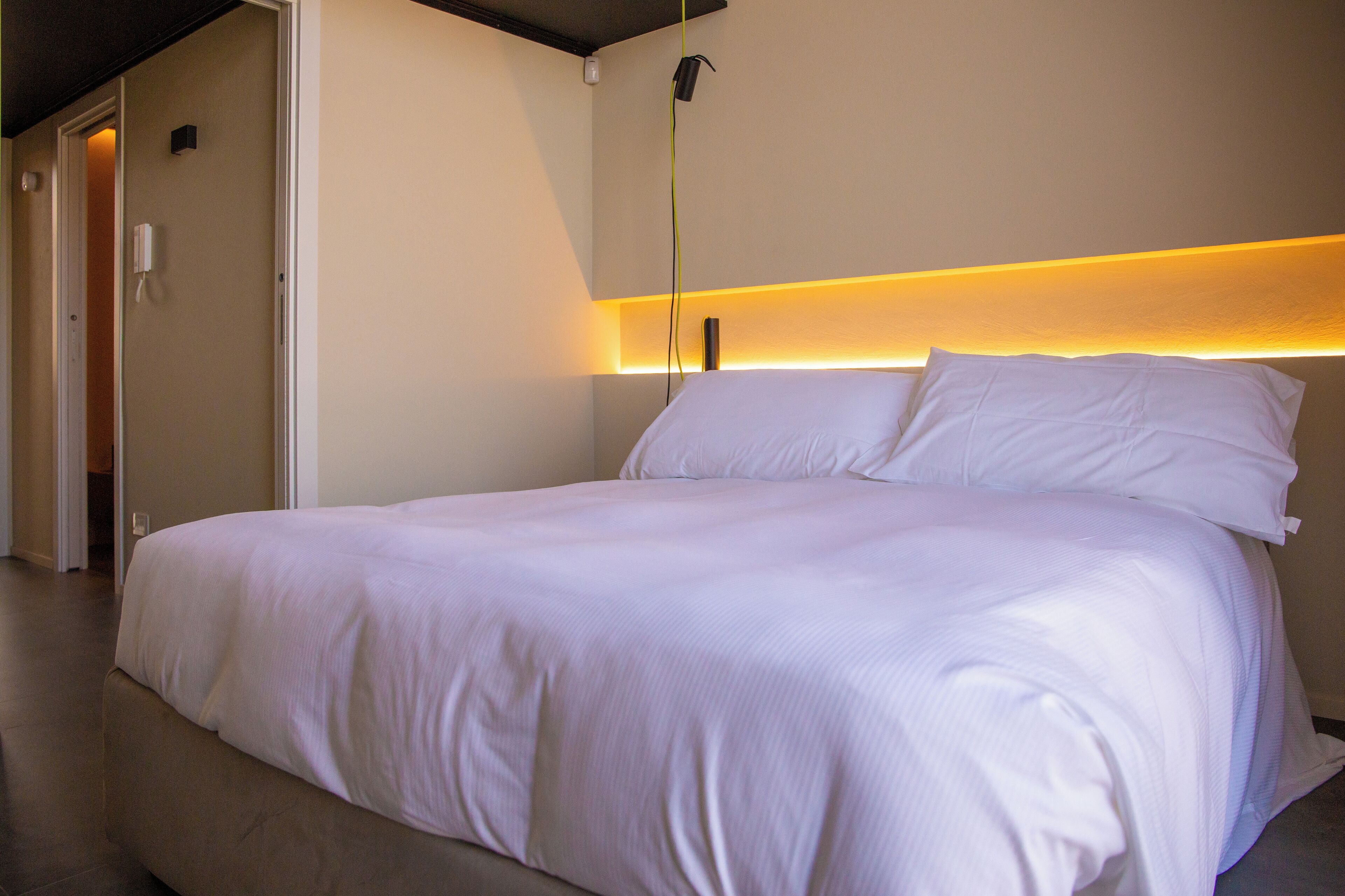 A neatly made bed with white linens in a modern hotel room.