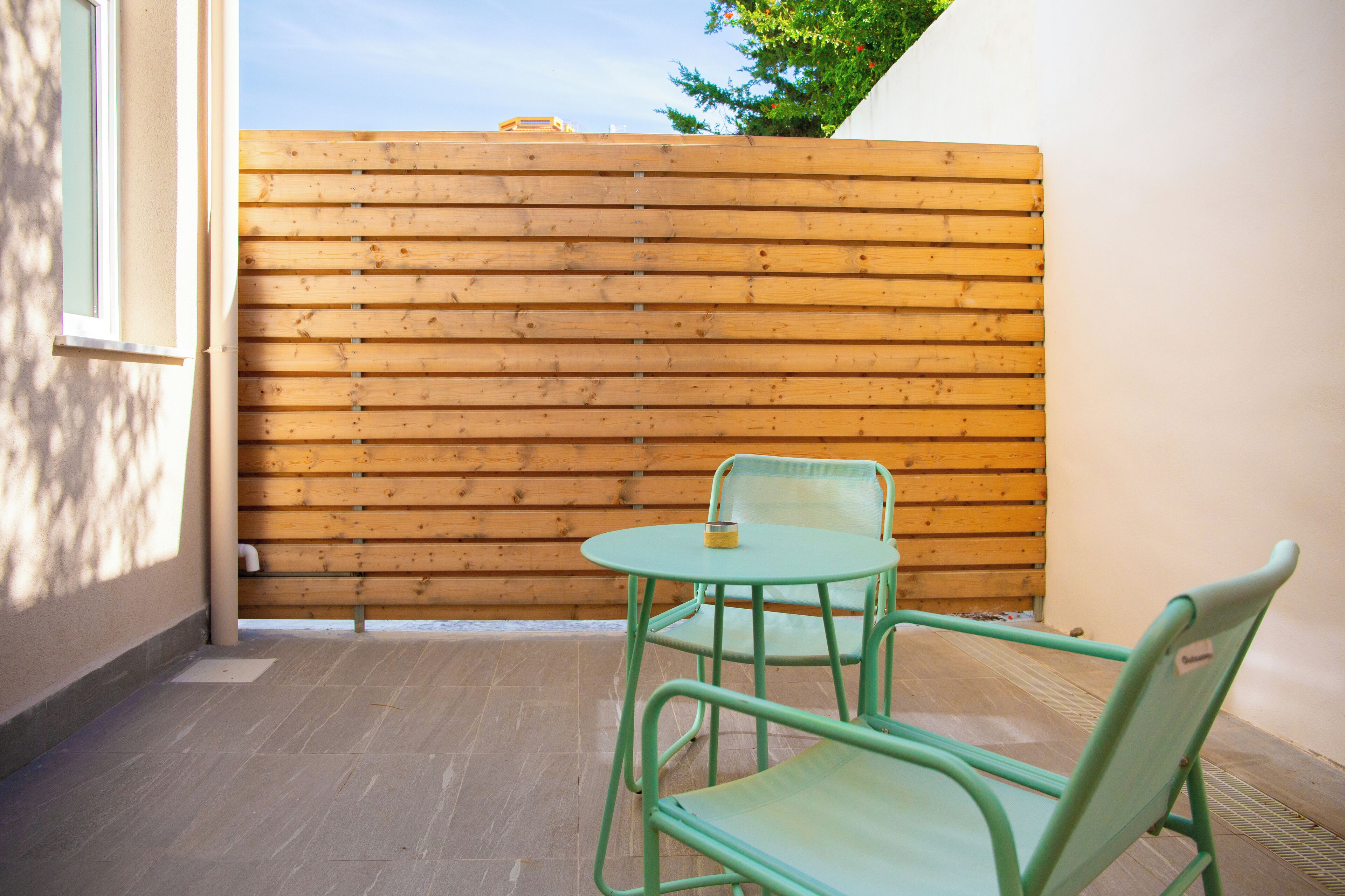 A small patio with a wooden fence, a round table, and two chairs.