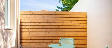 A small patio with a wooden fence, a round table, and two chairs.