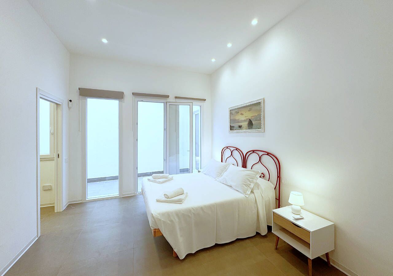 Un'ampia camera da letto con un letto grande, un comodino con una lampada e un quadro appeso al muro.