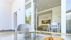 Un espace repas moderne avec une table en verre, une chaise blanche et une assiette de nourriture.