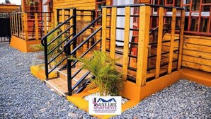 Un edificio de apartamentos de madera con una escalera que conduce a la entrada, rodeado de grava.