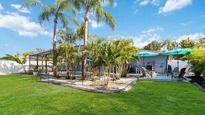 A backyard with a pool, palm trees, and a covered patio area. - FOX's Hidden Oasis 2 BR Pool Home 3 miles to AMI beaches (Bradenton)