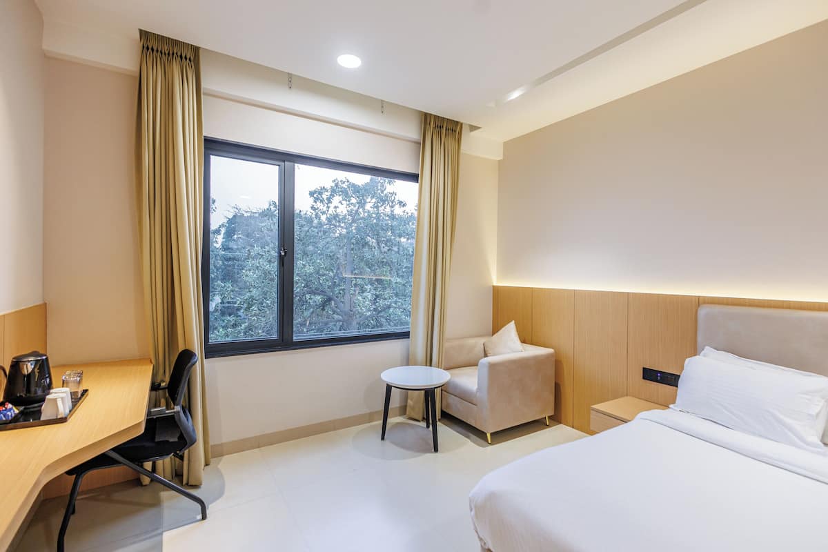 A hotel room with a bed, a desk with a chair, a small table, and a sofa.