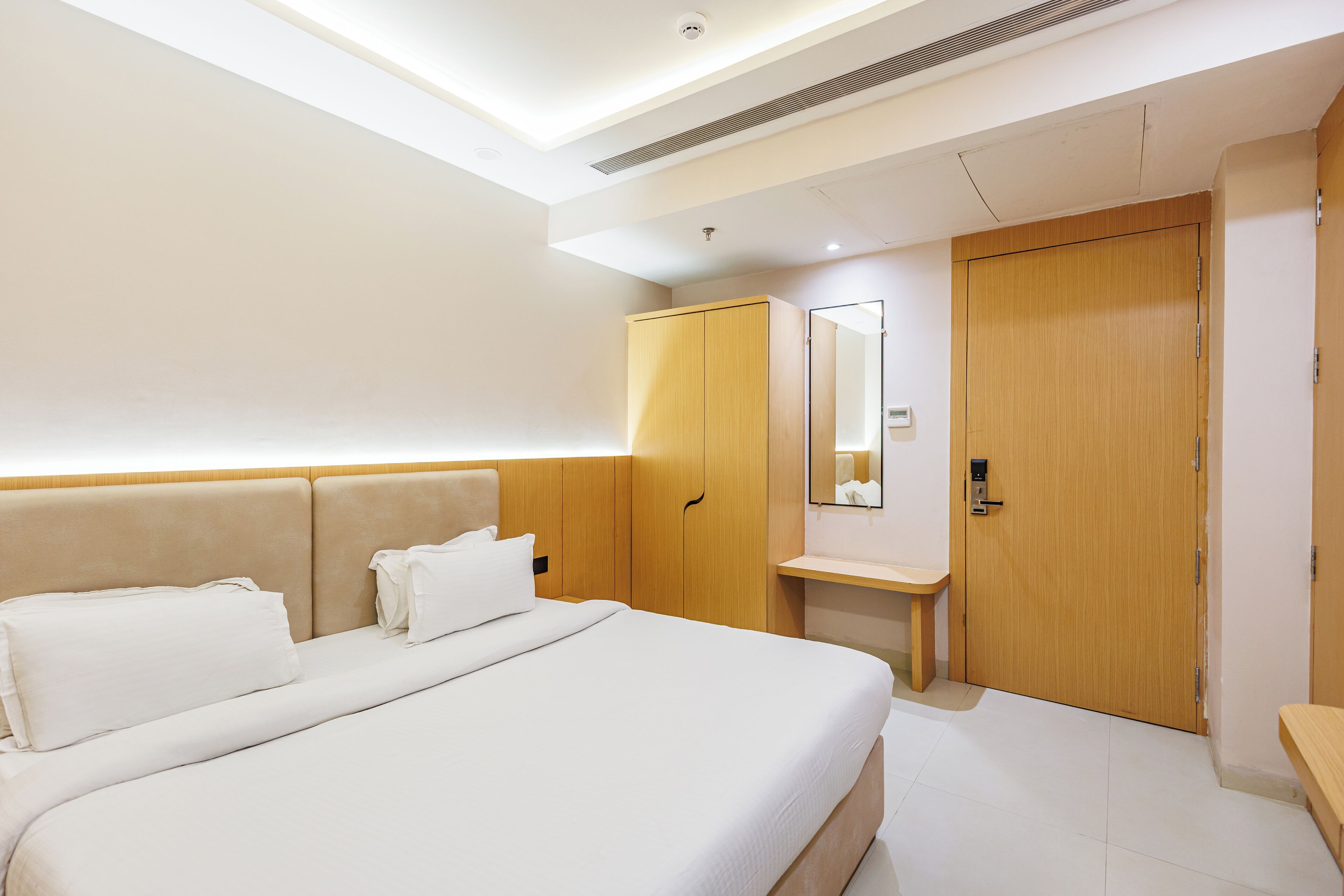 Ein Hotelzimmer mit einem großen Bett, einem Holzschrank, einem Nachttisch und einem Spiegel.