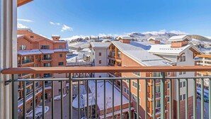 Une vue depuis un balcon donnant sur une ville enneigée, avec des bâtiments et des montagnes en arrière-plan.